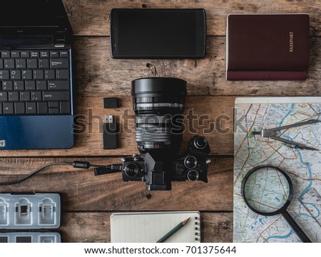 top view of work space photographer and travel concept with digital camera, battery charger camera, memory card storage box, external harddisk, flash, computer laptop on wooden background