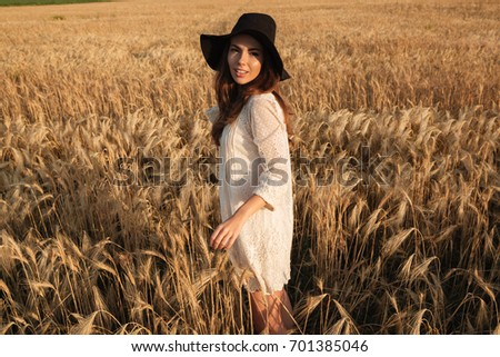 Picture of beautiful young woman standing in the field. Looking at camera.