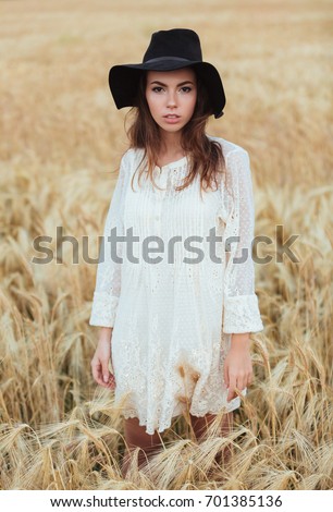 Picture of beautiful young woman standing in the field. Looking at camera.