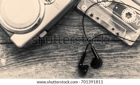 Vintage cassette player with earbuds and tape cassette on wooden background