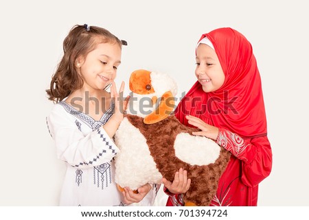 Happy little Muslim girls playing with sheep toy - celebrating Eid ul Adha - Happy Sacrifice Feast Royalty-Free Stock Photo #701394724