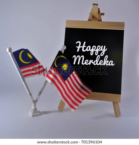 Independence Day Concept. Malaysia Flags with blackboard written Happy Merdeka isolated on white background.