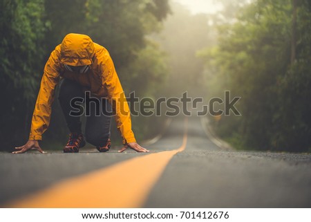 The woman in ready position.  she is running on the long road amidst the beautiful nature. Royalty-Free Stock Photo #701412676