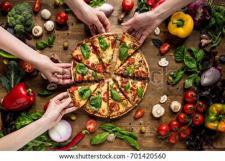 partial view of friends taking homemade pizza slices 