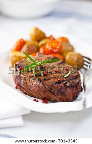 Grilled steak with baked vegetables and fresh rosemary. Concept for a tasty and healthy meal. Close up Royalty-Free Stock Photo #70143343