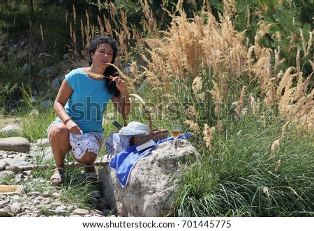 A beautiful young woman is having a picnic near the river