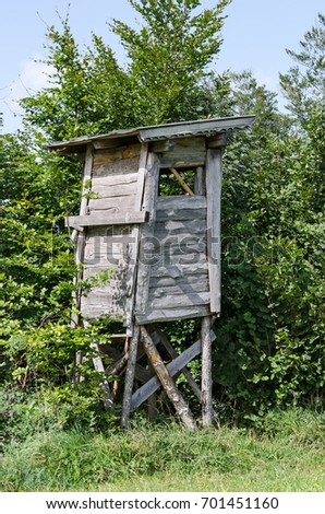 Wooden tree stand along the edge of a meadow, vertical view. Deer or box stand. Enclosed platform to elevate the hunter for better vantage point and keep him hidden. Heuberg, Salzburg, Austria. Photo.