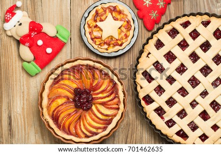 Homemade fruit pies from cherry, apples and peaches on light wooden background. Christmas decoration elements.