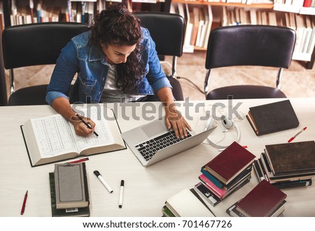 Young female student study in the school  library.She using laptop and learning online. Royalty-Free Stock Photo #701467726