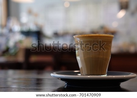 Glass of coffee latte on wooden table at coffee shop in the morning.