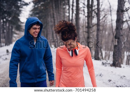 Photo of an athletic couple walking in the snow and having fun in the forest.