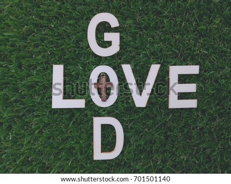 Words GOD, LOVE, wooden alphabets materials put on green grass field, vintage color and selective focus