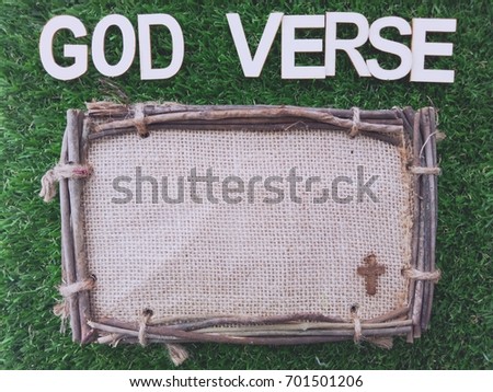 Old wooden frame with words GOD VERSE on green grass field, vintage color and selective focus with copy space