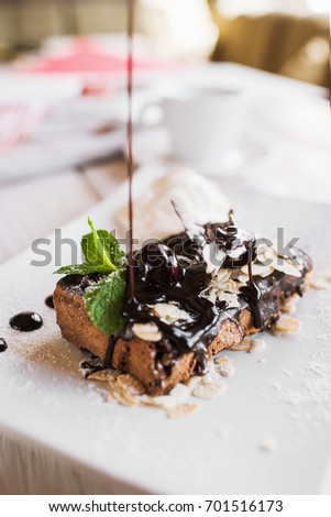 Process of decoration of chocolate pie by syrup. Delicious cake serving in restaurant with ice-cream ball and mint leaf, close up picture