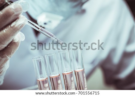 scientist dropping chemical liquid to flask with lab glassware background, Laboratory research concept,Researcher is dropping the reagent into test tube.