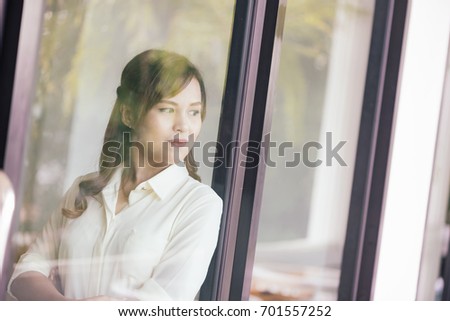 View of Through a glass window, Asian girl business thinking idea for a new project, freelance thinking idea for a new project in selective focus.