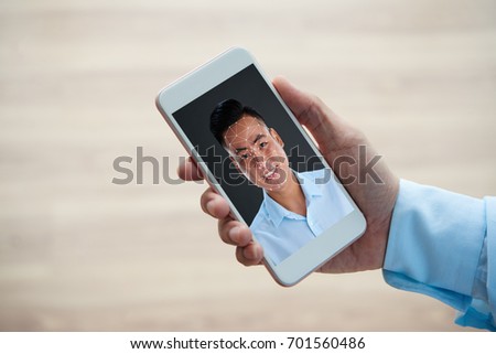 Smartphone with polygonal grid on face of smiling Vietnamese man