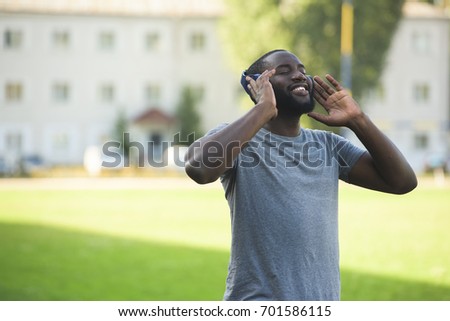 A handsome black man is enjoying listening to music, wearing headphones