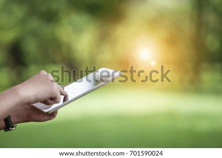 girl using a digital tablet outdoor at the park. Modern technology concept.digitally enhanced. Selective focus on the tablet.