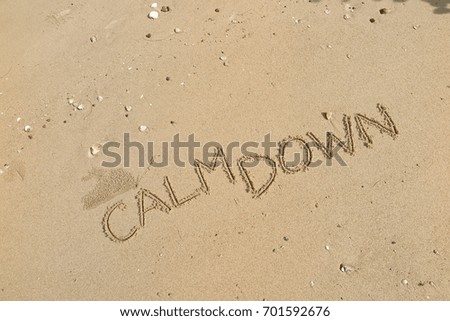 Handwriting  words "CALM DOWN" on sand of beach.