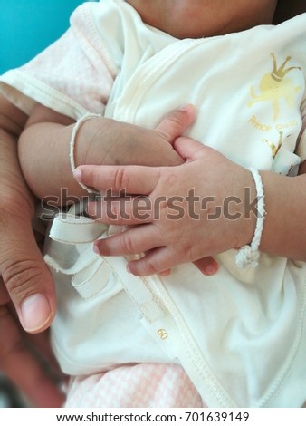 picture of baby holds hands together while lying on mother's lap giving a lot of different feeling confidence calm reassure peaceful. it is good and pleasure to look at 