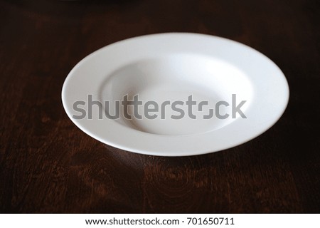 Empty white plate on a dark wooden brown table