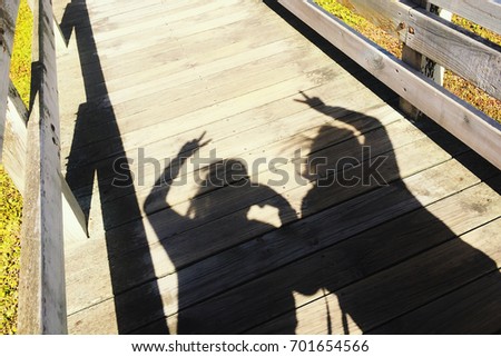 Best friend forever concept, the shadow of two people showing peace hand sign on wooden path walk way.
