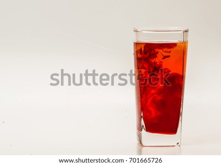 mixture of food coloring diffuse in water inside glass with empty copyspace area for slogan or advertising text message, over isolated grey background. 