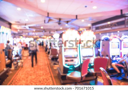 Blurred image slot machines, themed game, roulette slot poker 777, armed bandit with players at casino in Louisiana. Colorful illuminated light on row of digital machines. Gambling abstract background