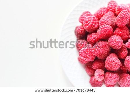 raspberries closeup on a white plate for the background