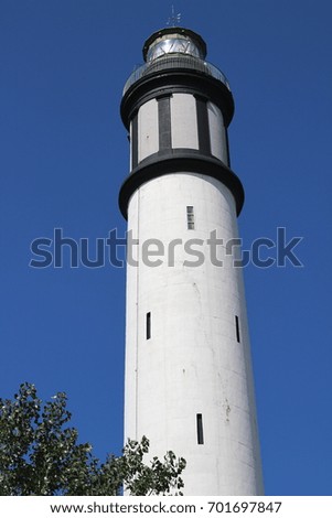 High of a white lighthouse on a background of cloudless blue sky