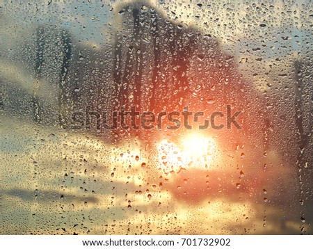 The sky with clouds and sun on background. Water drops on a window glass after the rain.