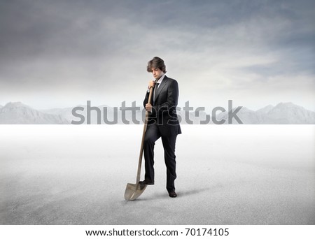 Businessman digging with a shovel in a desert Royalty-Free Stock Photo #70174105
