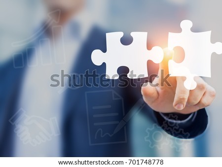 Mergers and acquisition concept with consultant touching icons of puzzle pieces representing the merging of two companies or joint venture, partnership Royalty-Free Stock Photo #701748778