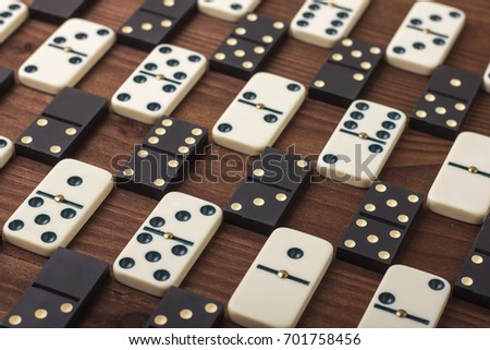 Dominoes are black and white. On a wooden background. The game is tabletop
