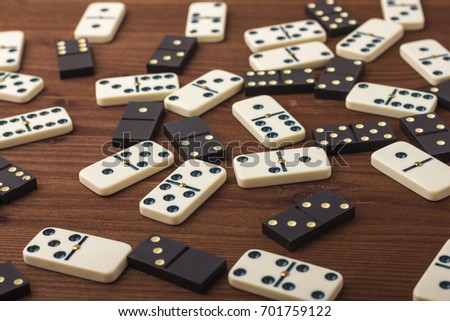 Dominoes are black and white. On a wooden background. The game is tabletop