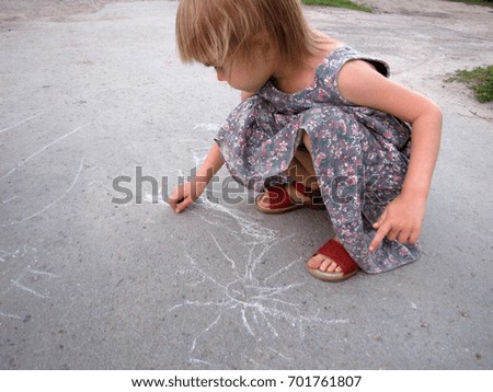   Girls is drawing sun on asphalt