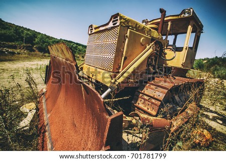 Vintage bulldozer. An abandoned old tractor with a bucket on a stone quarry. Old tractor in the field