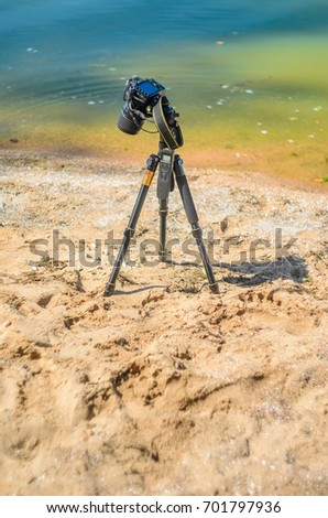 Camera on a tripod near the seaside removes of seashells on the sand. Photographic equipment in the process of shooting the landscape. Camera while taking a photo or time-lapse