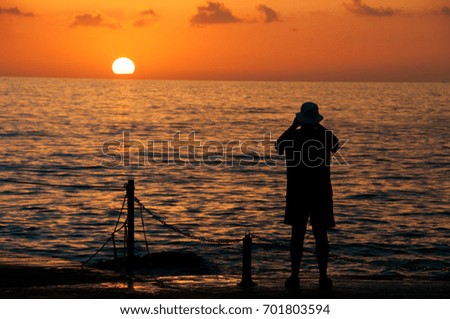 man is photographing a sunset against the background of the sea.