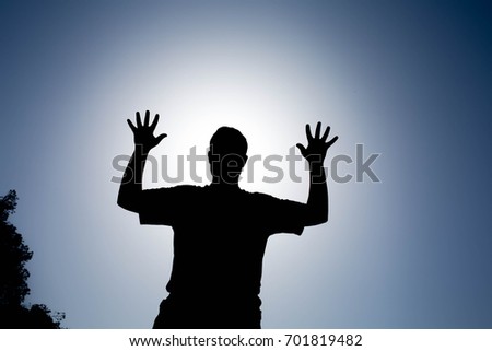 Silhouette of happy man with his hands up