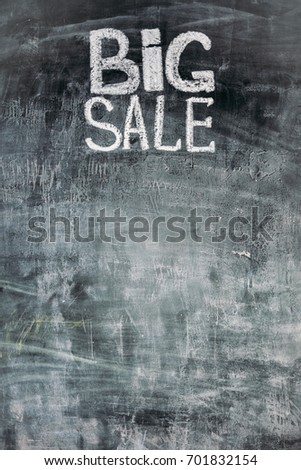 hand drawn lettering of big sale in chalk on black slate with copy space for your text