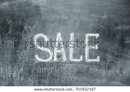 hand drawn lettering of sale in chalk on black slate with copy space for your text
