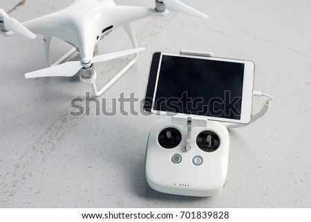 Drone with a remote control and a tablet on it on a gray concrete background. Quadcopter with camera ready to shoot video