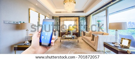 mobile phone with smart home app in modern living room Royalty-Free Stock Photo #701872057