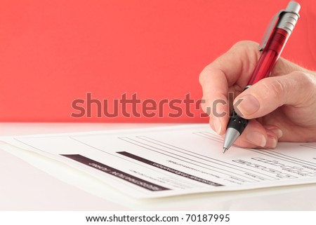 Red Themed Pen in Hand Completing Form