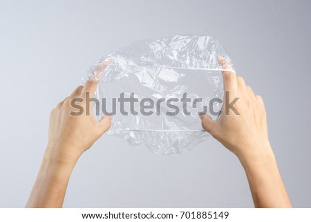 Hand holding disposable transparent plastic shower cap on white background Royalty-Free Stock Photo #701885149
