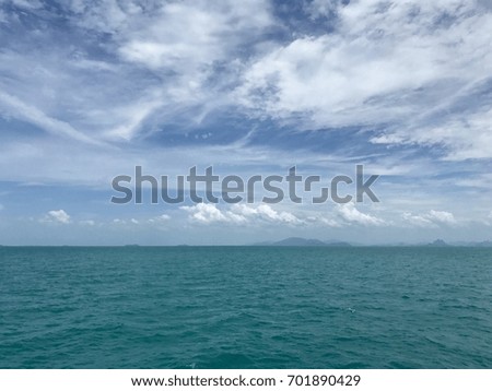 The scenic view of Andaman sea shows blue cloudy fluffy sky above the wavy ocean which is turquoise color and island in horizon.