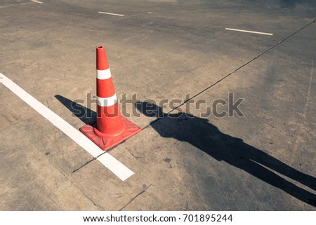 shadow of pedestrian with traffic cone on street