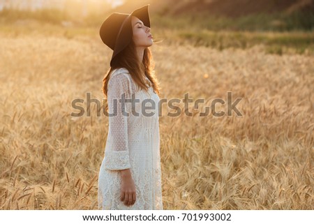 Picture of gorgeous young woman standing in the field. Looking aside.
